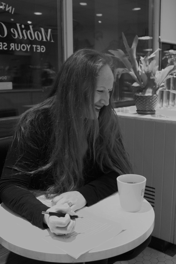Vanessa Brahmakshatriya, author, marks up manuscript pages while enjoying a coffee.